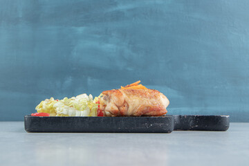 A wooden board of chicken fried meat with lettuce