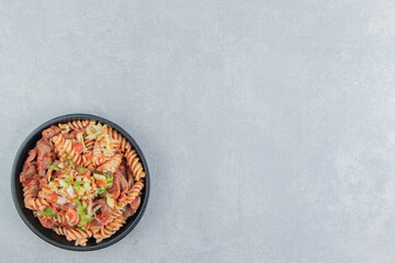 A black plate with spiral pasta with herbs