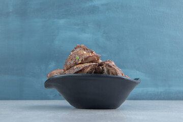 A black bowl of delicious meat on marble background