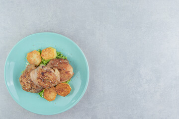 A blue plate of meat with fried sliced potatoes and lettuce