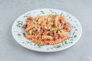 A white plate of spiral pasta with herbs