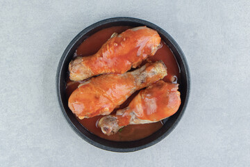 A black plate of fried meat in tomato sauce