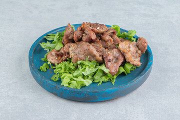 A wooden plate with delicious fried meat and lettuce