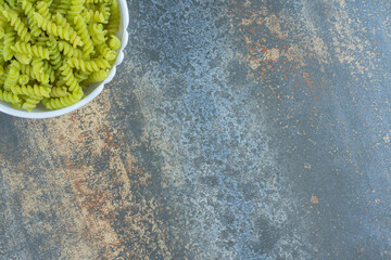 Green fusilli pasta, on the marble background