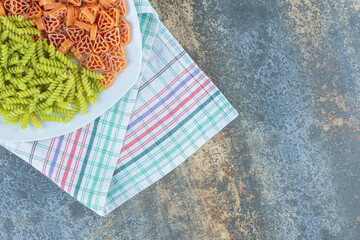 Hearth shaped pasta with fusilli pasta in plate, on the towel , on the marble background