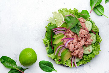 Tuna fish salad with avocado, cucumber, red onion and lettuce. White stone background, top view, copy space