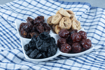 Different dried fruits in bowl, on the tea towel, on the marble background