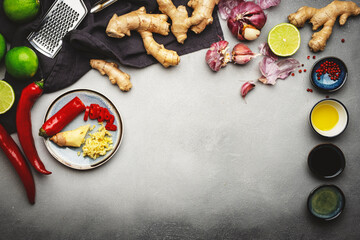 Asian cuisine ingredients, food background. Ginger, lime, chili pepper, garlic, soy sauce and rice vinegar on gray kitchen table. Healthy eating concept. Top view