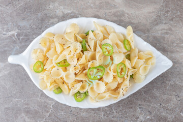 Peppered farfalle pasta on a fancy plate , on the marble background