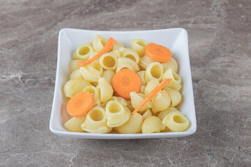 Delicious pasta with sliced carrot in bowl , on the marble background