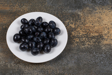 Fresh black grapes on white plate