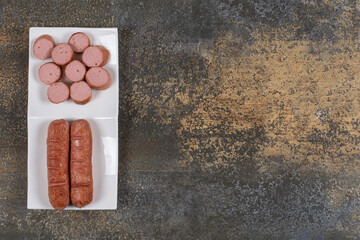 Fried sliced sausages on white square plate