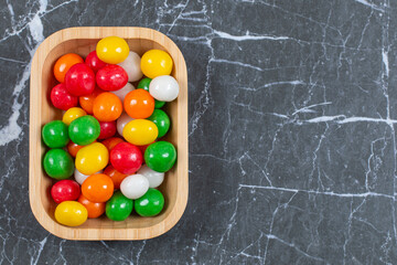 Plate of colorful candies on marble background
