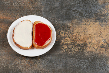 Toasts with strawberry jam and sour cream on white plate