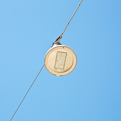 Single modern led street lamp hanging from a metal cable against a clear sky