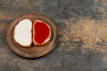 Toasts with strawberry jam and sour cream on wooden board