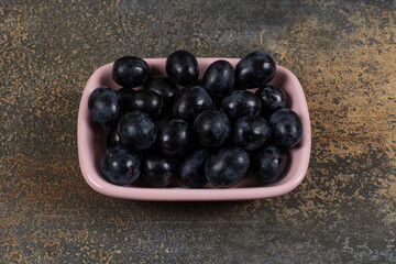 Bunch of black grapes in pink bowl