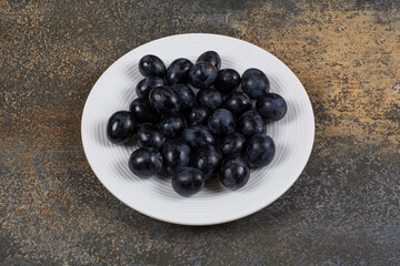 Fresh black grapes on white plate