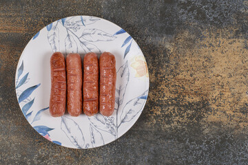 Grilled tasty sausages on colorful plate