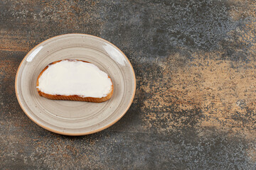 Slice of toast with sour cream on ceramic plate
