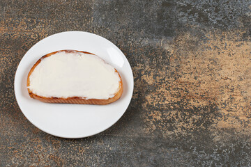 Slice of toast with sour cream on white plate