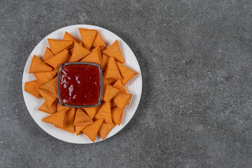 Triangle shaped chips and ketchup on white plate