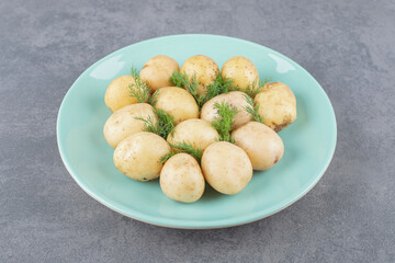 A blue plate of boiled potatoes with fresh dill