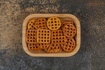 Tasty crispy crackers on wooden plate