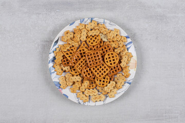 Plate of various salted crackers on stone background