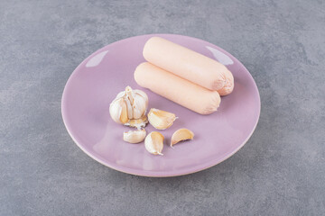A purple plate of boiled sausages with garlics