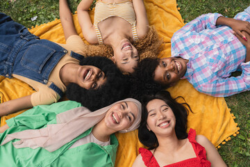 Happy youth, multiethnic women having fun lying on the grass in the park - Concept of diversity and...