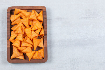 Delicious crunchy chips on wooden plate