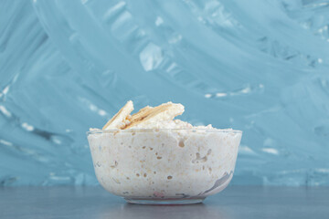 A glass plate of oatmeal porridge with slices of banana