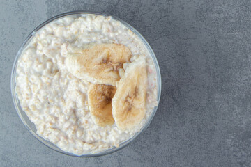 A glass plate of oatmeal porridge with slices of banana