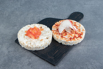 Crispy puffed rice toasts with tomatoes on wooden board