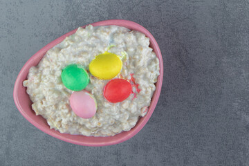 A pink plate of oatmeal porridge with colorful candies