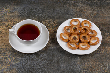 Plate of crackers and cup of tea on marble background