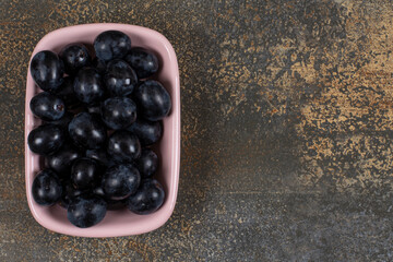 Bunch of black grapes in pink bowl