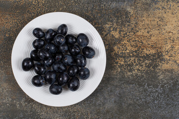 Fresh black grapes on white plate