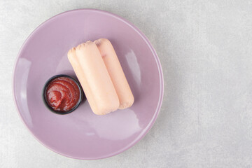 Fototapeta na wymiar Fresh boiled sausages and ketchup on purple plate