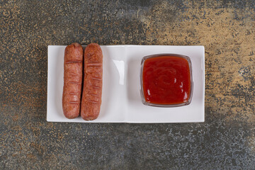 Fried sausages and ketchup on white plate