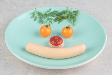 Sausages and vegetables placed on plate like smiling face