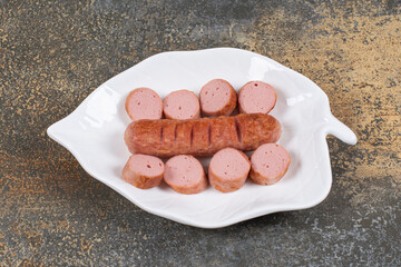 Grilled sliced sausages on white leaf shaped plate