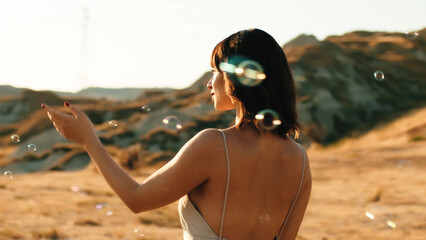 Pretty girl dances among the bubbles in a yellow field in the countryside