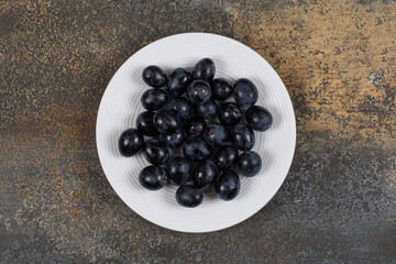 Fresh black grapes on white plate