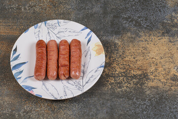 Grilled tasty sausages on colorful plate