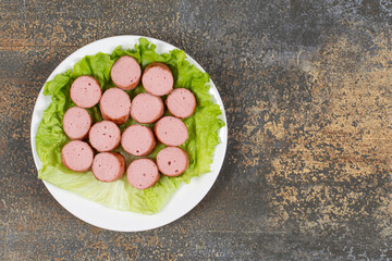 Grilled sliced sausages and lettuce on white plate