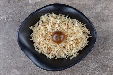 A bowl of grated pasta with tomato, on the marble background