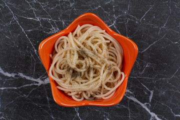 Fresh homemade spaghetti with spices in orange bowl