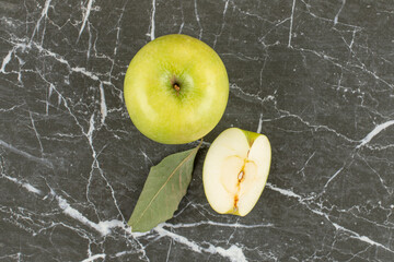 Top up view of green apples. Whole and sliced on grey background